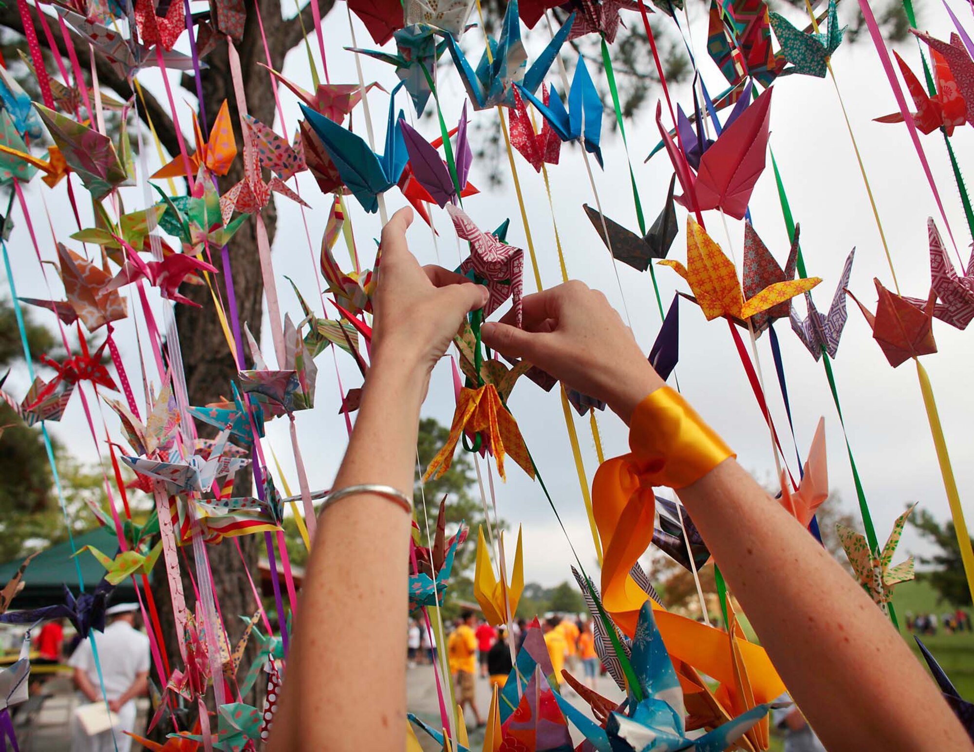 A participant hangs an origami crane, an international symbol of peace, hope and healing, during the Out of the Darkness Community Walk at Mount Trashmore Park in Virginia Beach, Va., Sept. 6, 2014. This year, U.S. Service members and civilians from the Hampton Roads community are set to join forces to promote suicide awareness during the walk at Mount Trashmore Park, Sept. 12, 2015. (Courtesy photo)