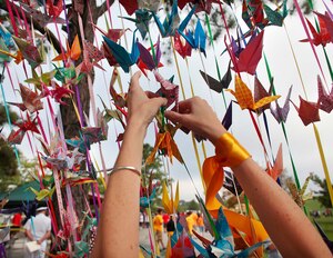 A participant hangs an origami crane, an international symbol of peace, hope and healing, during the Out of the Darkness Community Walk at Mount Trashmore Park in Virginia Beach, Va., Sept. 6, 2014. This year, U.S. Service members and civilians from the Hampton Roads community are set to join forces to promote suicide awareness during the walk at Mount Trashmore Park, Sept. 12, 2015. (Courtesy photo)