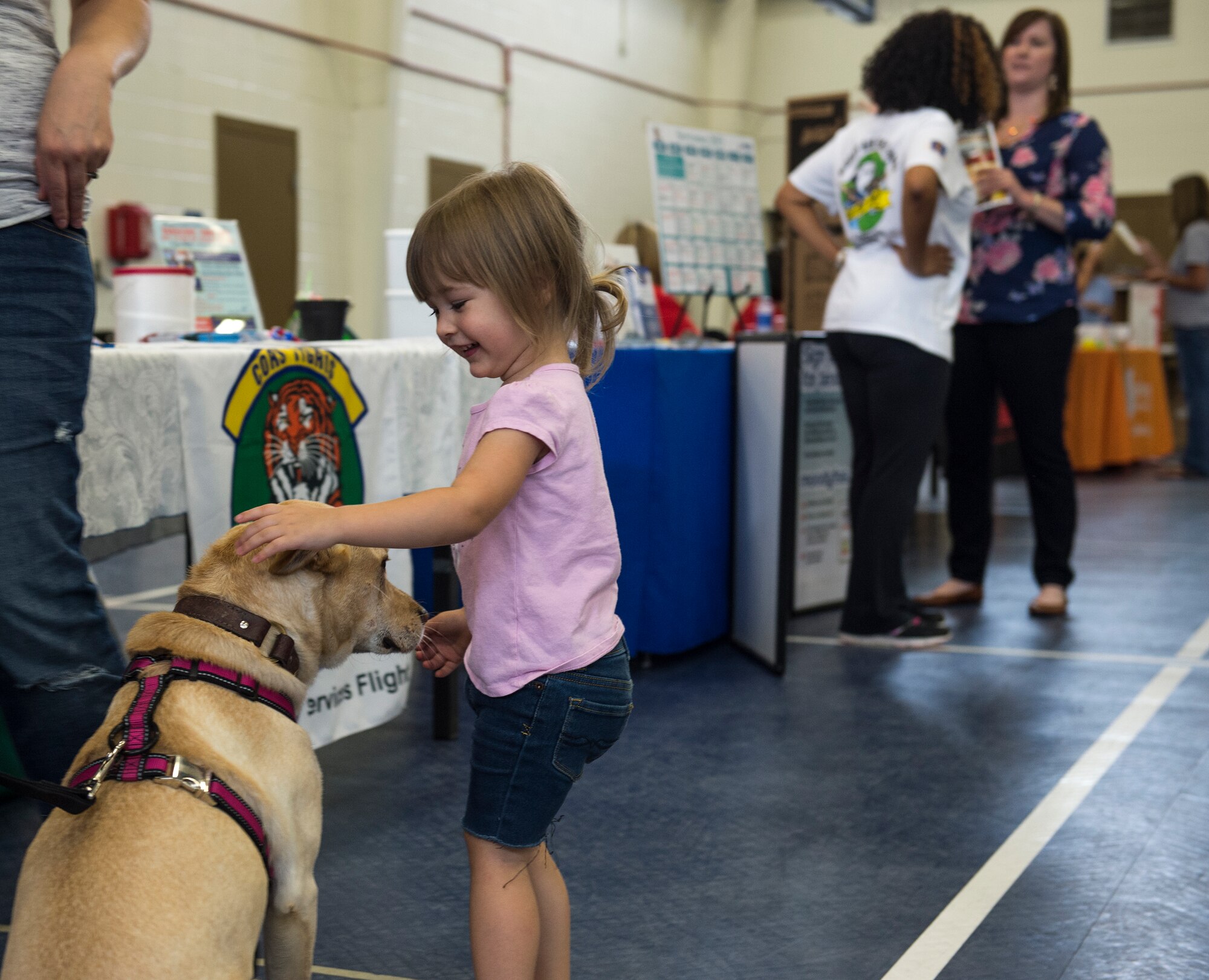 Margot LaRue, daughter of U.S. Air Force Staff Sgt. Jesse LaRue, pets a dog from a local humane society during the deployment expo in the youth center gymnasium Aug. 29, 2015 at Moody Air Force Base, Ga. There were many community services that offered information to Airmen and families ranging from the local humane society to a literacy center. (U.S. Air Force photo/Tech. Sgt. Zachary Wolf)