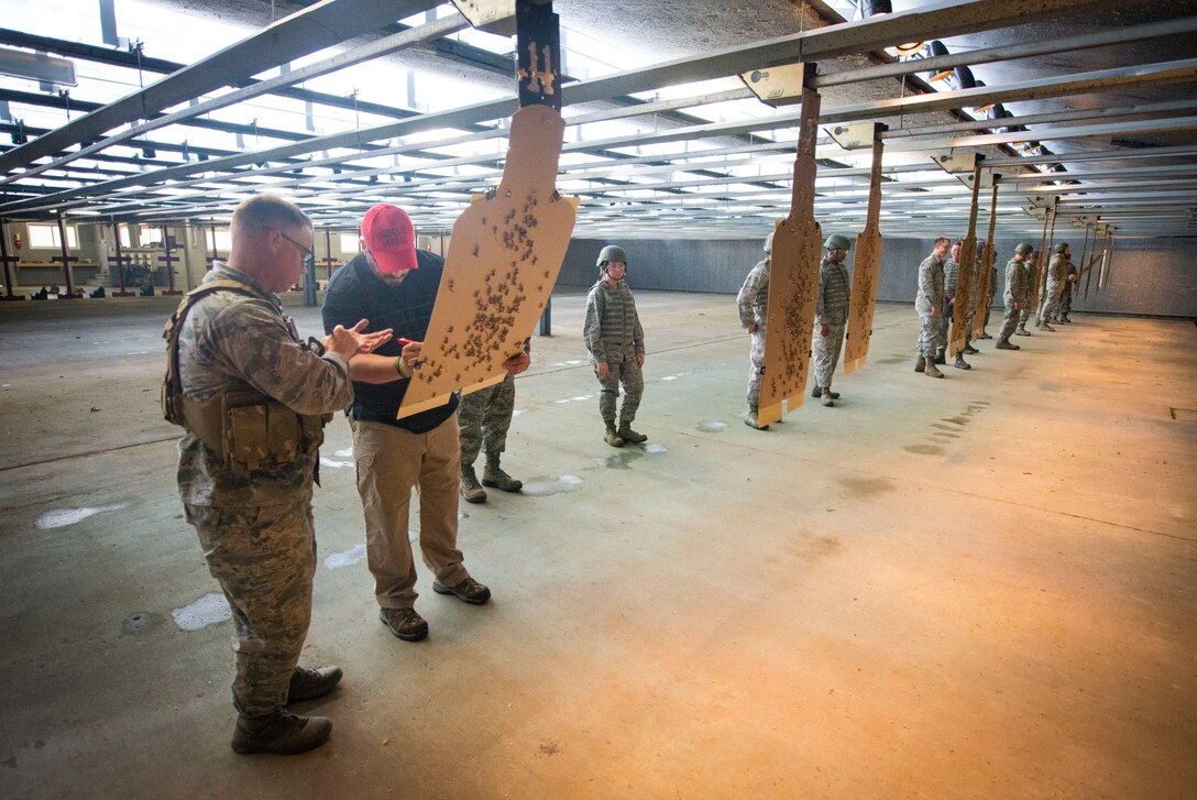 Danny Hubbard, 11th Security Support Squadron combat arms training and maintenance instructor, inspects an Airman's target during weapons training on Joint Base Andrews, Md., Sept. 1, 2015. Prior to qualifying, CATM instructors ensure the weapons are "zeroed" to each shooter's eye. (U.S. Air Force photo by Staff Sgt. Chad C. Strohmeyer/Released)