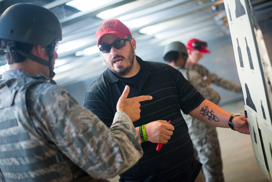 Danny Hubbard, 11th Security Support Squadron combat arms training and maintenance instructor, discusses proper technique with an Airman during weapons training on Joint Base Andrews, Md., Sept. 1, 2015. Prior to qualifying, CATM instructors spend several hours teaching different shooting techniques and positions, weapons cleaning and safety. (U.S. Air Force photo by Staff Sgt. Chad C. Strohmeyer/Released)