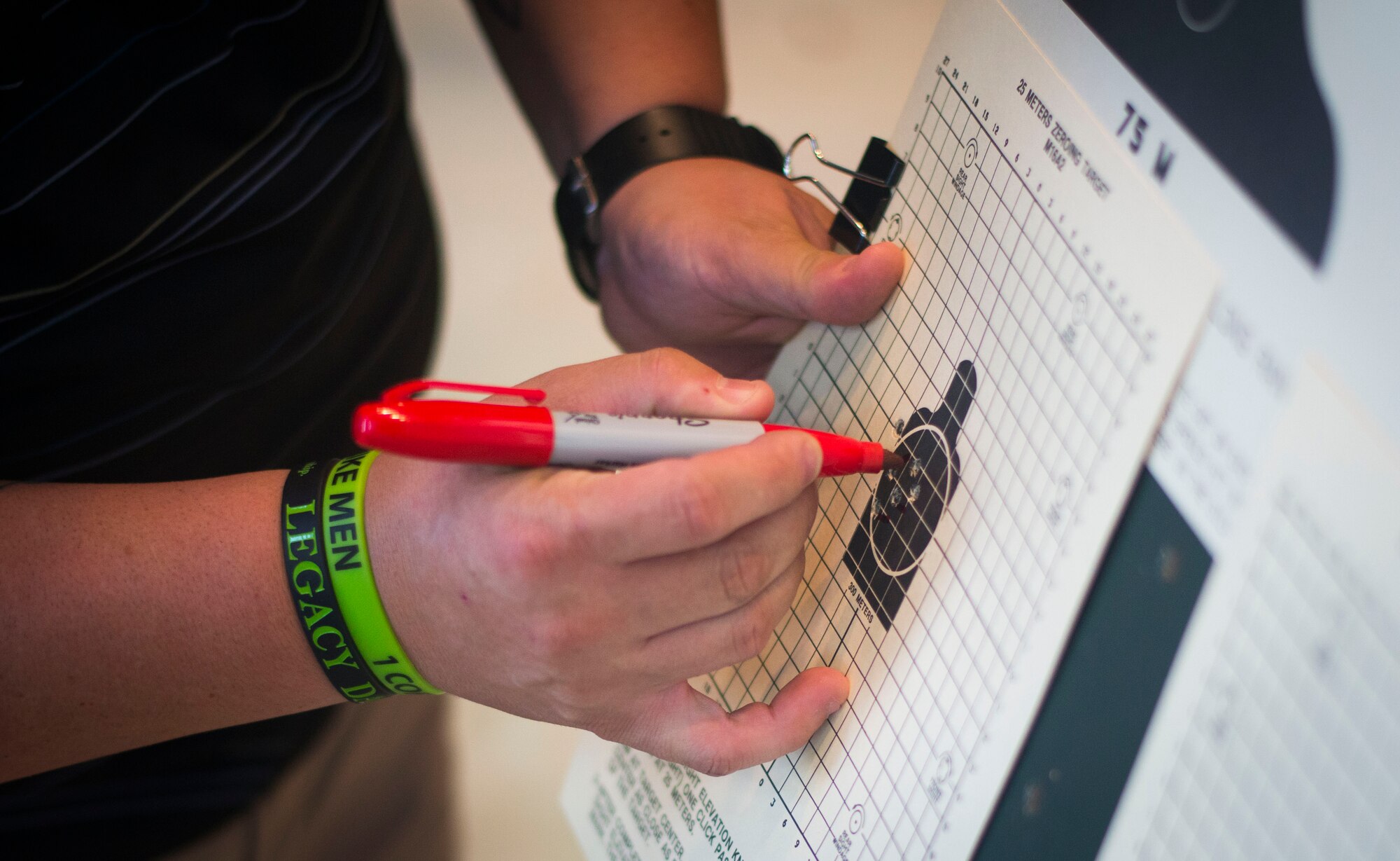 A combat arms training and maintenance instructor makes a mark next to each bullet hole during weapons training on Joint Base Andrews, Md., Sept. 1, 2015. Marking each hole allows the shooter/instructor to clearly see the most current shots. (U.S. Air Force photo by Staff Sgt. Chad C. Strohmeyer/Released)