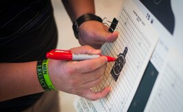 A combat arms training and maintenance instructor makes a mark next to each bullet hole during weapons training on Joint Base Andrews, Md., Sept. 1, 2015. Marking each hole allows the shooter/instructor to clearly see the most current shots. (U.S. Air Force photo by Staff Sgt. Chad C. Strohmeyer/Released)