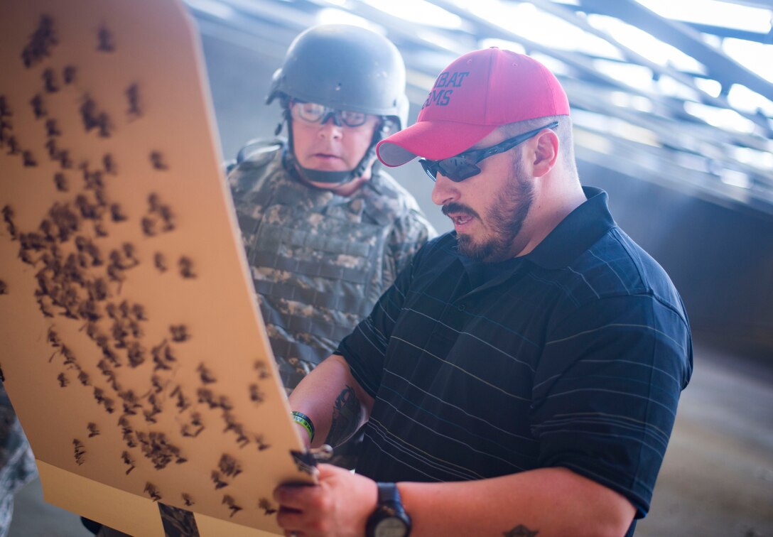 Danny Hubbard, 11th Security Support Squadron combat arms training and maintenance instructor, inspects an Airman's target during weapons training on Joint Base Andrews, Md., Sept. 1, 2015. Prior to qualifying, CATM instructors ensure the weapons are "zeroed" to each shooter's eye. (U.S. Air Force photo by Staff Sgt. Chad C. Strohmeyer/Released)