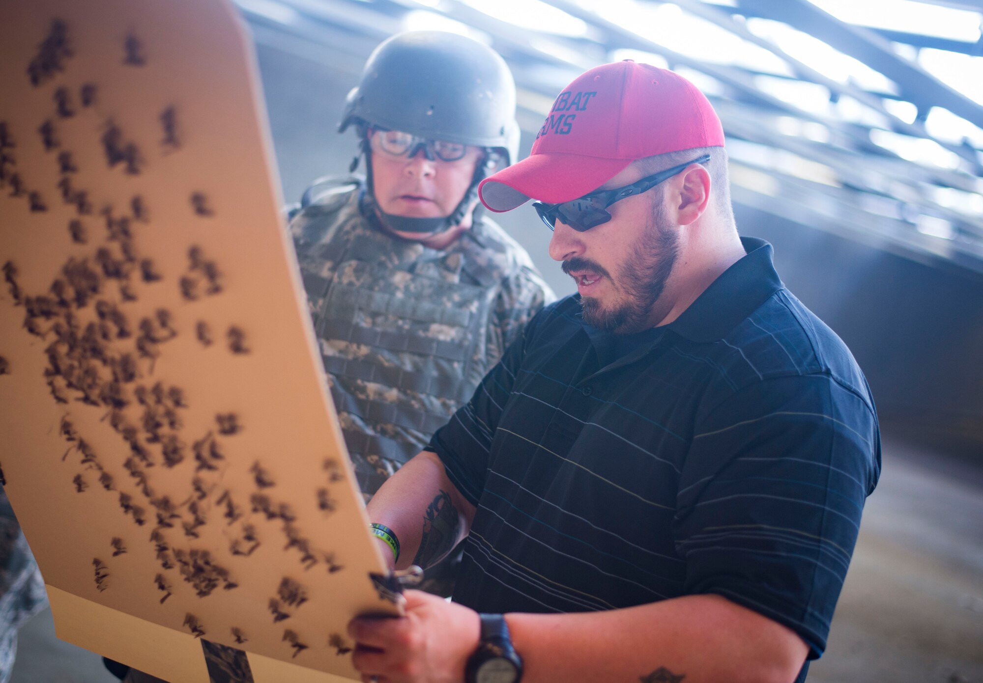 Danny Hubbard, 11th Security Support Squadron combat arms training and maintenance instructor, inspects an Airman's target during weapons training on Joint Base Andrews, Md., Sept. 1, 2015. Prior to qualifying, CATM instructors ensure the weapons are "zeroed" to each shooter's eye. (U.S. Air Force photo by Staff Sgt. Chad C. Strohmeyer/Released)