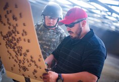 Danny Hubbard, 11th Security Support Squadron combat arms training and maintenance instructor, inspects an Airman's target during weapons training on Joint Base Andrews, Md., Sept. 1, 2015. Prior to qualifying, CATM instructors ensure the weapons are "zeroed" to each shooter's eye. (U.S. Air Force photo by Staff Sgt. Chad C. Strohmeyer/Released)