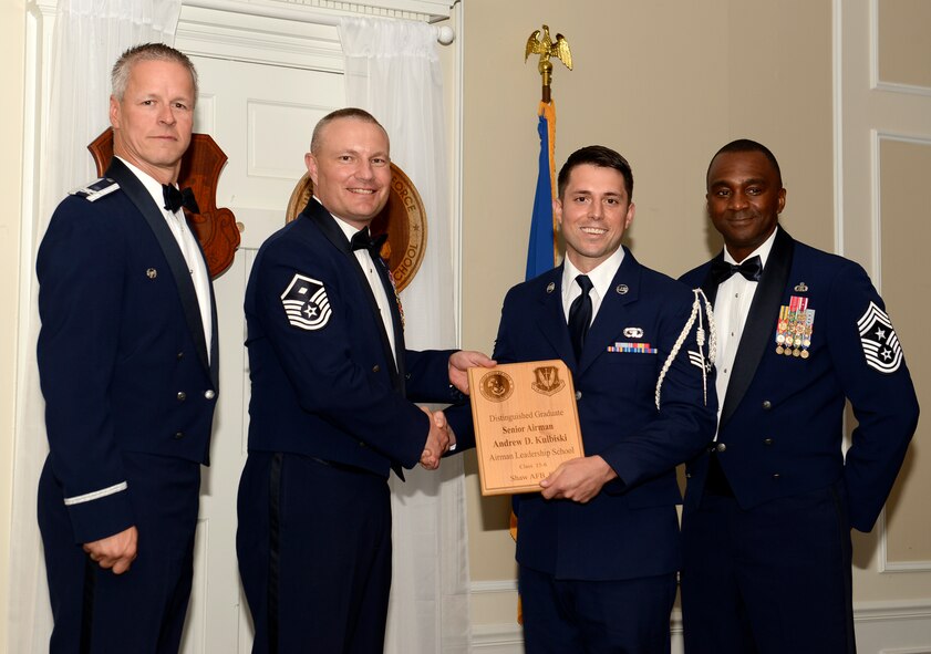 U.S. Air Force Senior Airman Andrew Kulbiski, 31st Intelligence Squadron (right), receives a distinguished graduate award for Class 15-6 of the Senior Master Sgt. David B. Reid Airman Leadership School from Master Sgt. Gregory Spiczka, 20th Security Forces Squadron first sergeant, and 20th Fighter Wing leadership, at Shaw Air Force Base, S.C., Aug. 27, 2015. The distinguished graduate awards are given to the top 10 percent of the class for total point accumulation. (U.S. Air Force photo by Airman 1st Class Christopher Maldonado/Released)