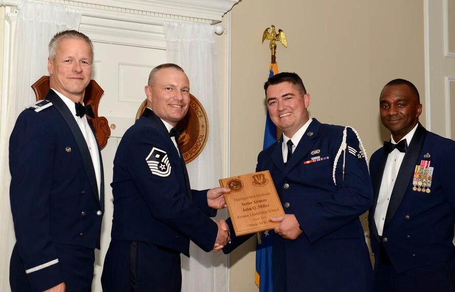 U.S. Air Force Senior Airman John Miller, 31st Intelligence Squadron (right), receives a distinguished graduate award for Class 15-6 of the Senior Master Sgt. David B. Reid Airman Leadership School from Master Sgt. Gregory Spiczka, 20th Security Forces Squadron first sergeant, and 20th Fighter Wing leadership at Shaw Air Force Base, S.C., Aug. 27, 2015. The distinguished graduate awards are given out to the top 10 percent of the class for total point accumulation. (U.S. Air Force photo by Airman 1st Class Christopher Maldonado/Released)
