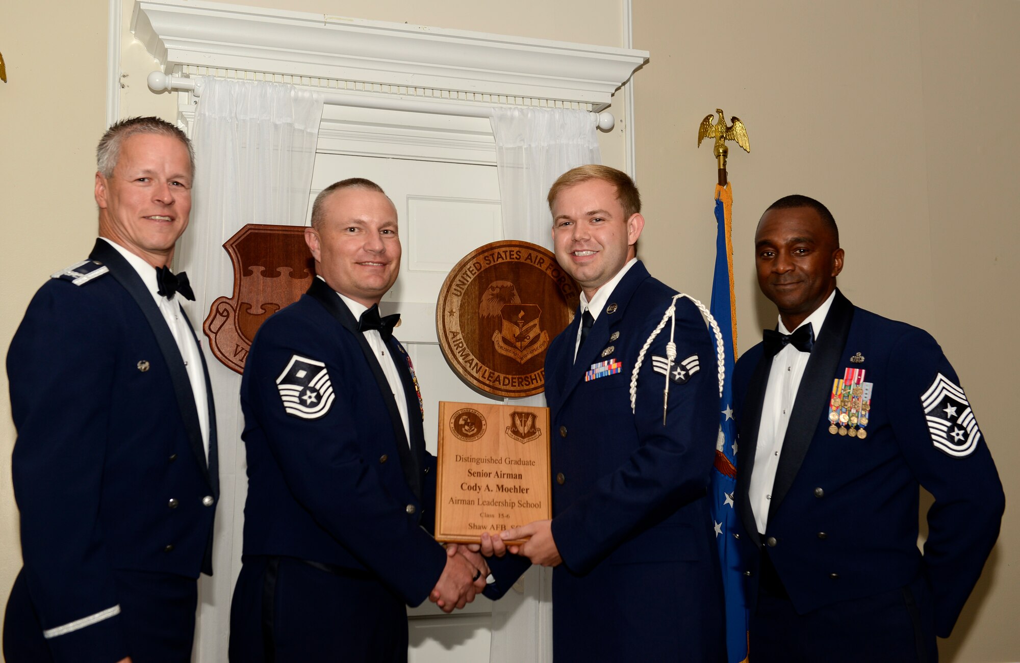 U.S. Air Force Senior Airman Cody Moehler, 20th Civil Engineer Squadron (right), receives a distinguished graduate award for Class 15-6 of the Senior Master Sgt. David B. Reid Airman Leadership School from Master Sgt. Gregory Spiczka, 20th Security Forces Squadron first sergeant, and 20th Fighter Wing leadership, at Shaw Air Force Base, S.C., Aug. 27, 2015. The distinguished graduate awards are given to the top 10 percent of the class for total point accumulation. (U.S. Air Force photo by Airman 1st Class Christopher Maldonado/Released)