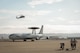 Maintenance Airmen from the 513th Aircraft Maintenance Squadron watch as a Navy MH-60 Seahawk helicopter flies behind an E-3C Sentry on Aug. 24 at Naval Air Station North Island in Coronado, Calif. After each mission, the Airborne Warning and Control System aircraft requires careful inspection and checks to ensure safety of flight. (U.S. Air Force photo by Staff Sgt. Caleb Wanzer)