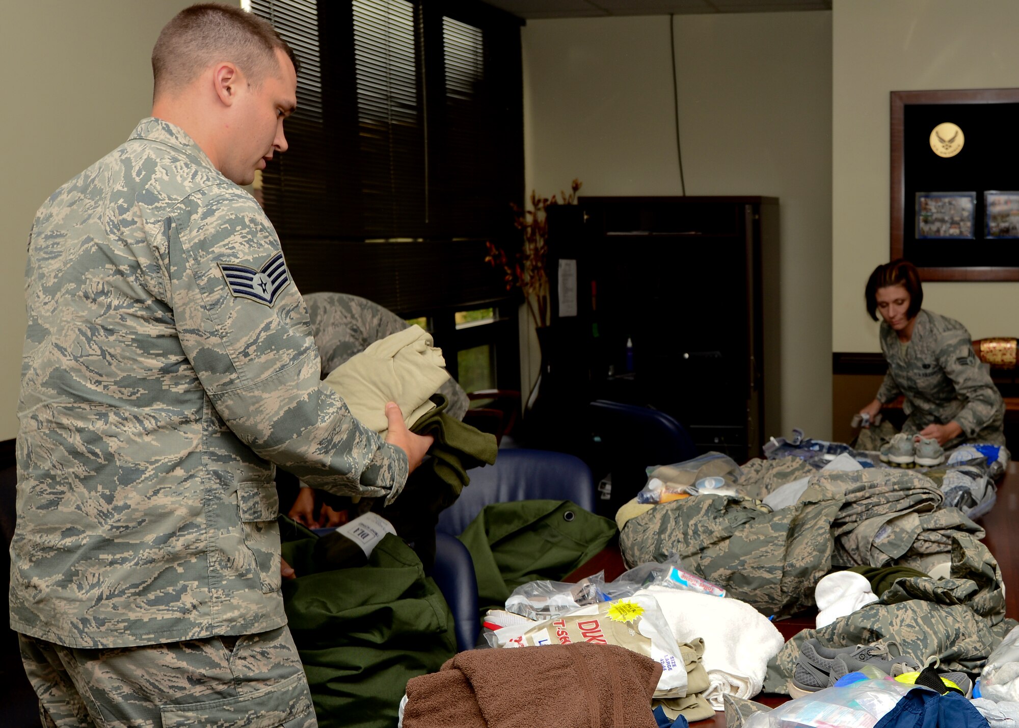 U.S. Air Force Staff Sgt. Robert Vineyard, 633rd Comptroller Squadron military pay noncommissioned officer in charge of, and Senior Airmen Melissa Crocker, 633rd CPTS, military pay technician, sort required gear during a deployment readiness exercise at Langley Air Force Base, Va., Aug 27, 2015. The exercise tested 633rd Air Base Wing Airmen’s ability to rapidly deploy within 72 hours of notification orders. (U.S. Air Force photo by Airmen 1st Class Derek Seifert/ Released)
