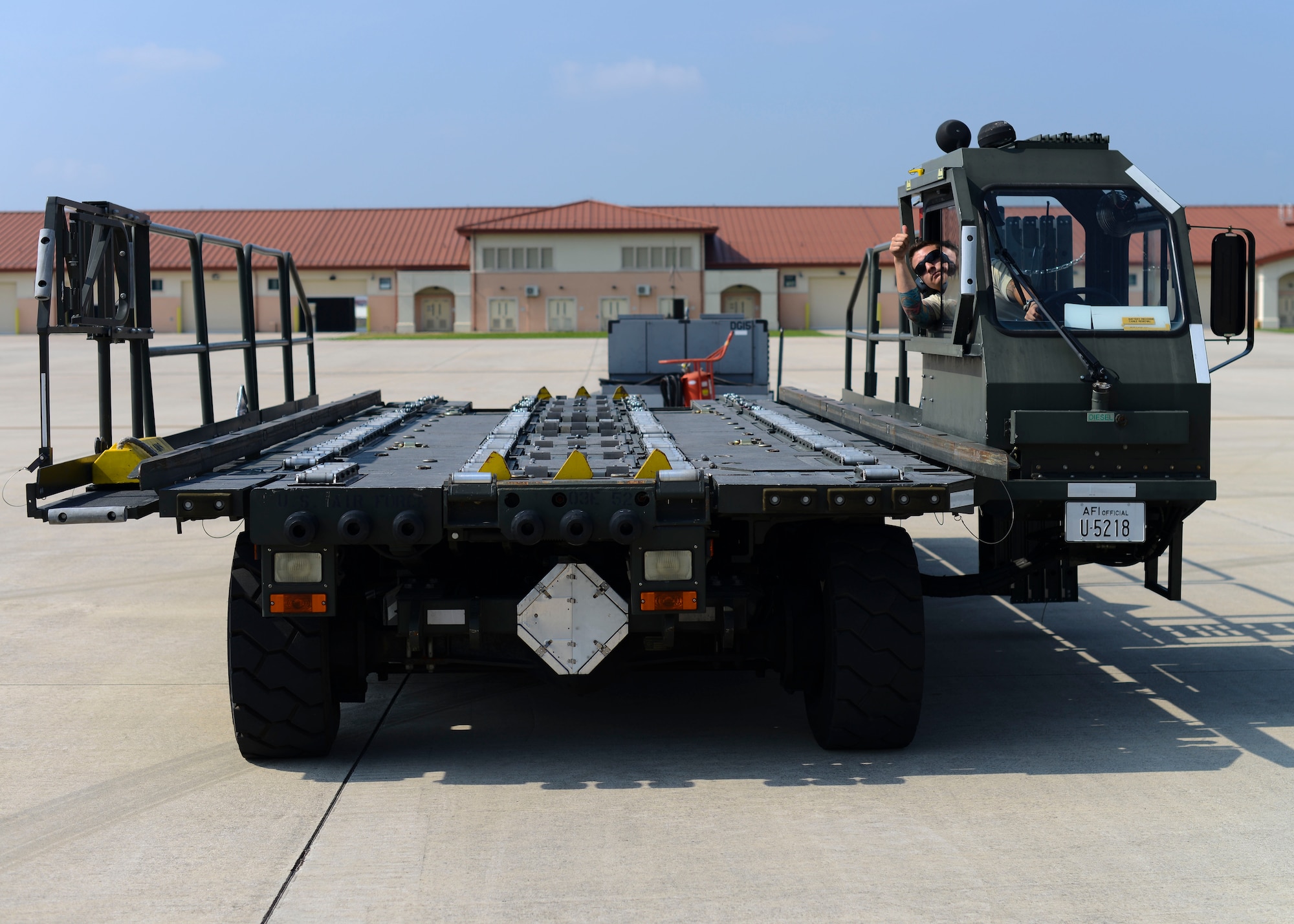 U.S. Air Force Senior Airman Jeremy Stoughton, 724th Air Mobility Squadron aircraft services specialist, approaches a C-130 Super Hercules with a container transporter, Aug. 28, 2015, at Aviano Air Base, Italy. The container transporter’s load surface is similar to the interior of a C-130 for easy uploading and downloading of equipment. (U.S. Air Force photo by Senior Airman Austin Harvill/Released)