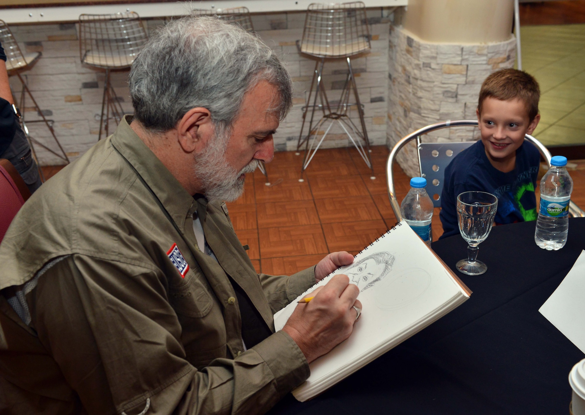 Sam Viviano, a National Cartoonist Society member on tour with the USO, draws a portrait of a child Aug. 27, 2015, at Incirlik Air Base, Turkey. Viviano is the art director of Mad Magazine. (U.S. Air Force photo by Senior Airman Michael Battles/Released)