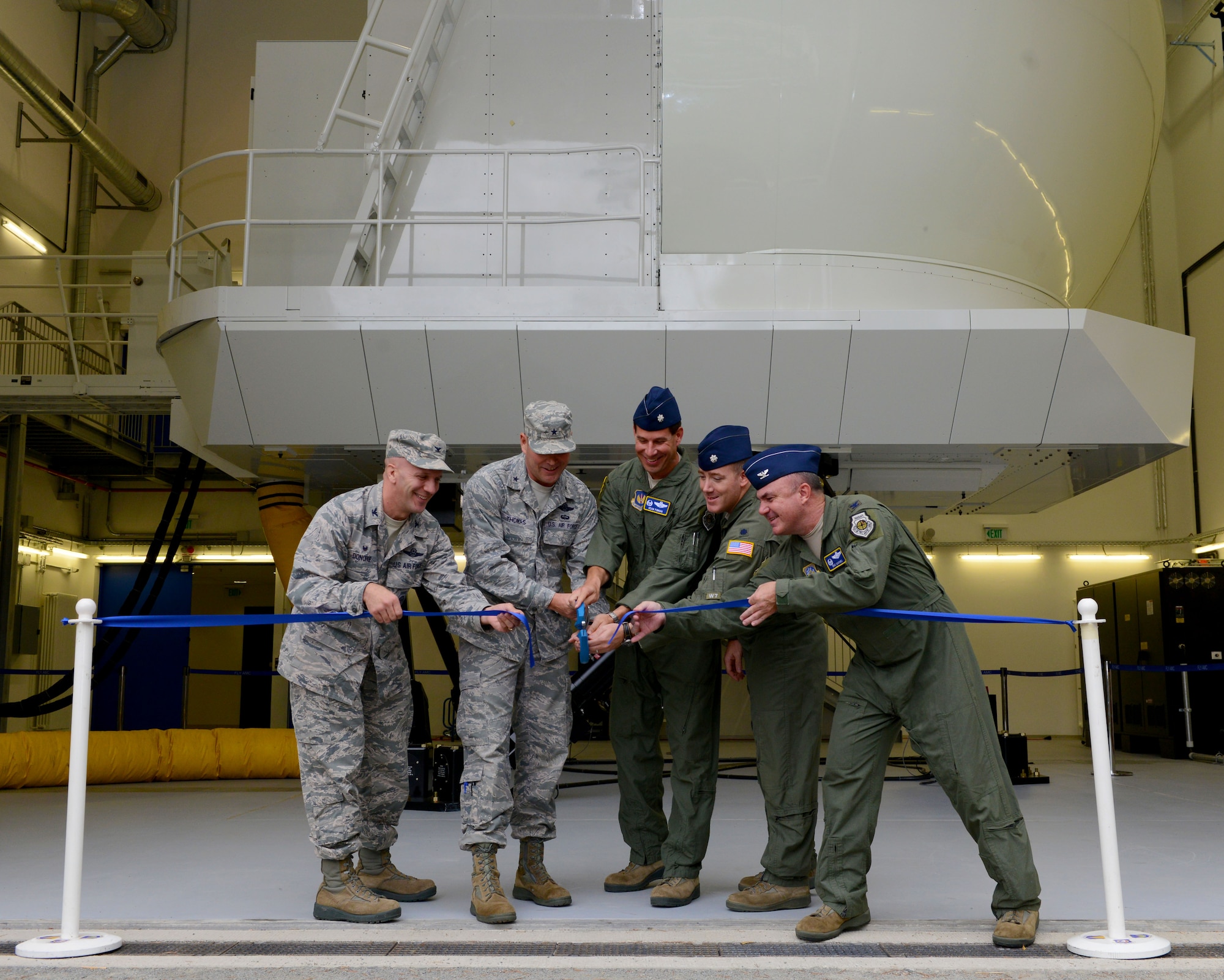 Brig. Gen. Jon T. Thomas, second from left, 86th Airlift Wing commander, and other members of the 86th AW cut a ribbon during the opening ceremony of the C-130J Super Hercules Flight Simulator Aug. 24, 2015, at Ramstein Air Base, Germany. According to Thomas, the experience gained from practicing high-density, high-difficulty missions in the simulator will be priceless. (U.S. Air Force photo/Senior Airman Timothy Moore)