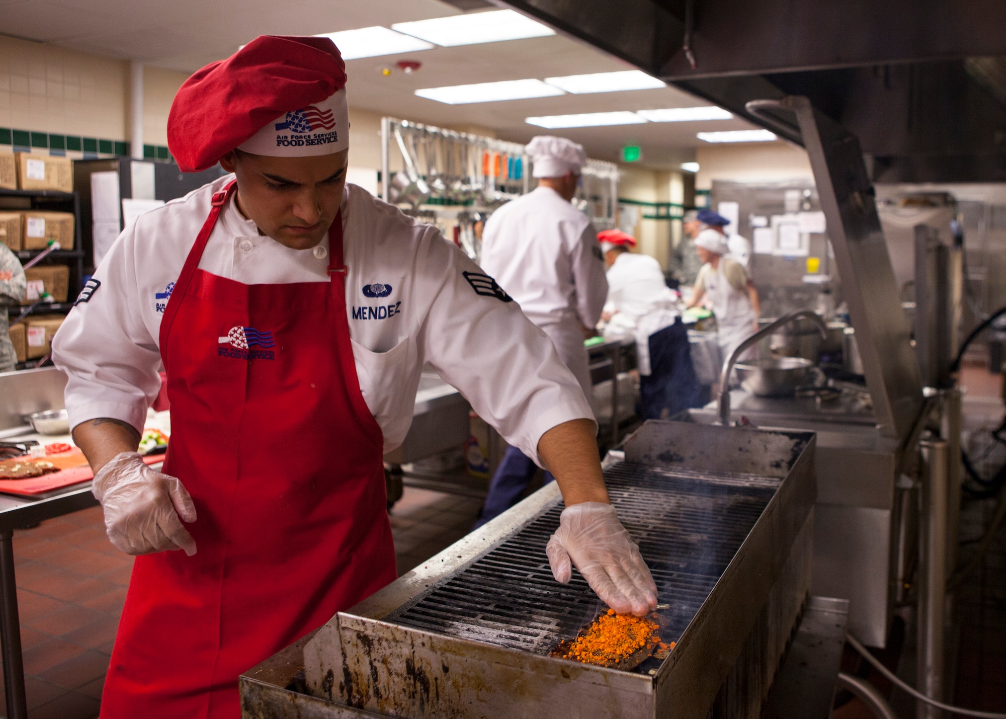 Senior Airman Joashua Mendez, 90th Force Support Squadron food service specialist, spreads a crumble made of cheese crackers on a steak during a culinary competition held at the Chadwell Dining Facility on F.E. Warren Air Force Base, Wyo., Aug. 27, 2015. Three teams of three chefs were pitted against each other vying for a spot to compete at the Global Strike Challenge. (U.S. Air Force photo by Lan Kim)