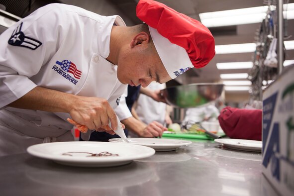 Airman 1st Class Ruel Abastas, 90th Force Support Squadron missile chef, decorates a plate with chocolate syrup for a dessert dish during an Iron Chef competition at the Chadwell Dining Facility on F.E. Warren Air Force Base, Wyo., Aug. 27, 2015. Ninetieth Force Support Squadron chefs had to create an entree incorporating the secret ingredient -- cheese crackers with peanut butter, along with a dessert dish within the hour time limit. (U.S. Air Force photo by Lan Kim)
