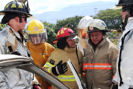 SOTO CANO AIR BASE, Honduras - Miguel Matus, a firefighter from the Belize National Fire Service (center), translates from English to Spanish for his team members from different Central American nations, during a vehicle extrication practice for CENTAM SMOKE, Aug. 27, 2015. CENTAM SMOKE, a quarterly exercise hosted by Joint Task Force-Bravo at Soto Cano Air Base, Honduras, allows participants to share experiences and knowledge in order to develop lasting relationships and to improve interoperability between nations.  (U.S. Army photo by Maria Pinel)
 

