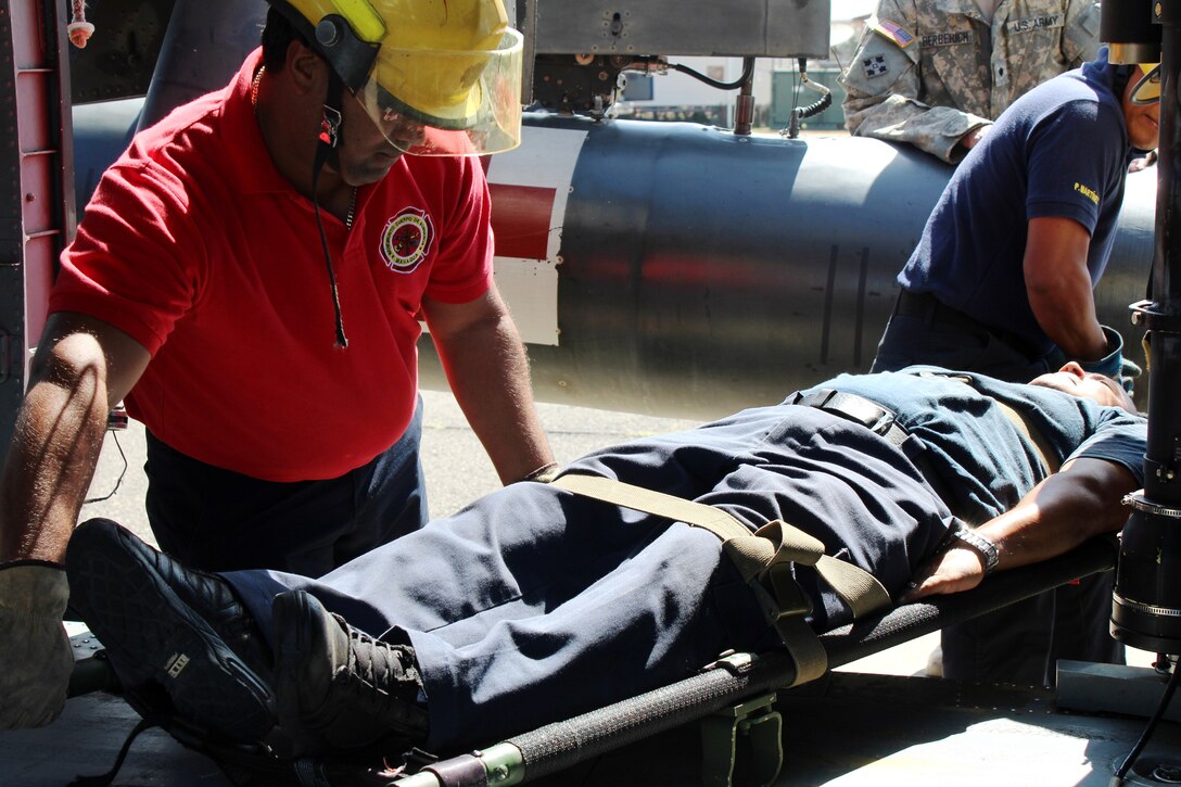 SOTO CANO AIR BASE, Honduras - Miguel Matus (front center), a firefighter from the Belize National Fire Service, volunteers as the “victim”, while his team members load him onto a UH-60 Helicopter during a practice involving the loading and unloading of patients Aug. 27, 2015. This was one event in the week-long CENTAM SMOKE exercise, a quarterly firefighting exercise hosted by Joint Task Force-Bravo at Soto Cano Air Base, Honduras.  (U.S. Army photo by Maria Pinel)
 
