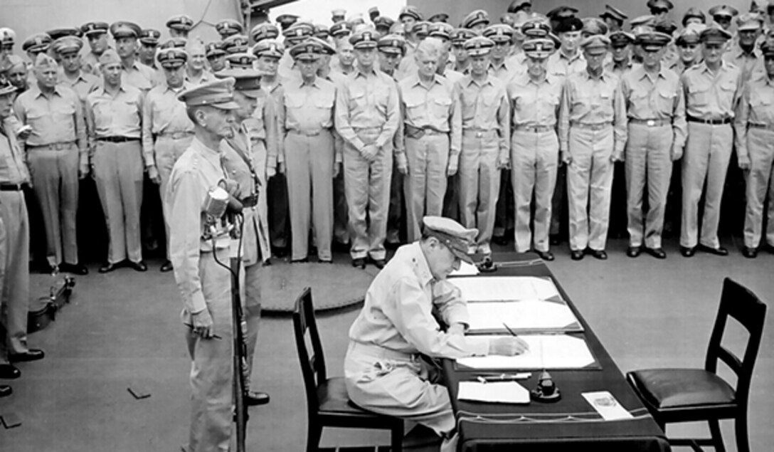 Allied sailors and officers watch Army Gen. Douglas MacArthur sign documents during the surrender ceremony aboard USS Missouri.