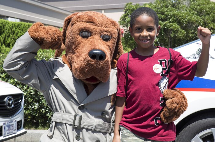 Nehemiah Hinds, an event participant, flexes with McGruff, the Provost Marshal’s Office mascot, at Child Safety Day Event aboard Marine Corps Air Station Iwakuni, Japan, Aug. 27, 2015. The event provided kids and parents the opportunity to meet safety officers and learn about staying safe on a daily basis. (U.S. Marine Corps photo by Lance Cpl. Nicole Zurbrugg/Released)