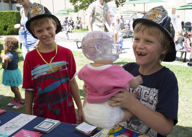 Kennon Lowry, left, and Jackson Lowry learn how to properly hold a baby at Child Safety Day Event aboard Marine Corps Air Station Iwakuni, Japan, Aug. 27, 2015. The doll’s head lights up to demonstrate the parts of the brain that are affected when an infant is shaken or not properly supported. The event helped kids learn personal safety through interactive activities and games. (U.S. Marine Corps photo by Lance Cpl. Nicole Zurbrugg/Released)