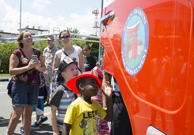 A crowd peers into a firetruck at Child Safety Day Event aboard Marine Corps Air Station Iwakuni, Japan, Aug. 27, 2015. Children and parents crowded around several safety vehicles on display for the event. The kids had the opportunity to sit in the driver’s seat of firetrucks, a police cruiser and an ambulance, while blasting the sirens, honking the horns and talking over the loud speakers. (U.S. Marine Corps photo by Lance Cpl. Nicole Zurbrugg/Released)