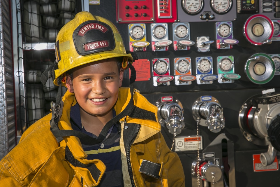Isaac Vanegas, 11, son of Ivette Vanegas, dons Combat Center Firefighter’s gear during the Behavior Health Family Fun Night at Heritage Park, Aug. 28, 2015. The event served to bring the community together and highlight the resources available to the families aboard the installation. (Official Marine Corps photo by Pfc. Levi Schultz/Released)