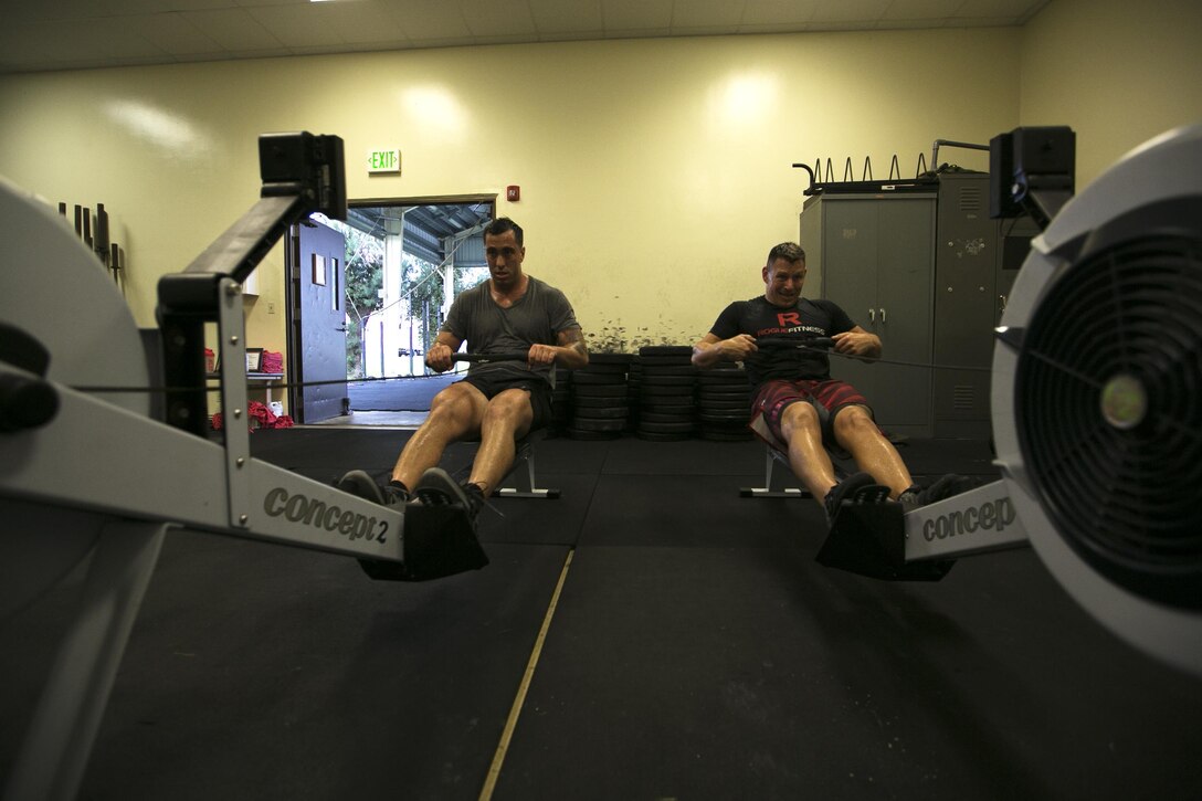 Sgt. Stephen Johnson, left, and Master Sgt. Chad Kiehl exercise on a rowing machine during a morning workout Aug. 28 in the Shogun Crossfit gym on Kadena Air Base. Kiehl and Johnson met while stationed in Okinawa and immediately began to benefit from each other’s strengths and weaknesses. Johnson, the stronger of the two, admired Keihl for his exceptional endurance while Keihl felt pushed to match Johnson’s physical strength. Johnson is a combat videographer and Keihl is the photography chief with Combat Camera, G-3/5; operations, training and plans; Marine Corps Installations Pacific-Marine Corps Base Camp Butler.  (U.S. Marine Corps Photo by Lance Cpl. Daniel Jean-Paul/Released)