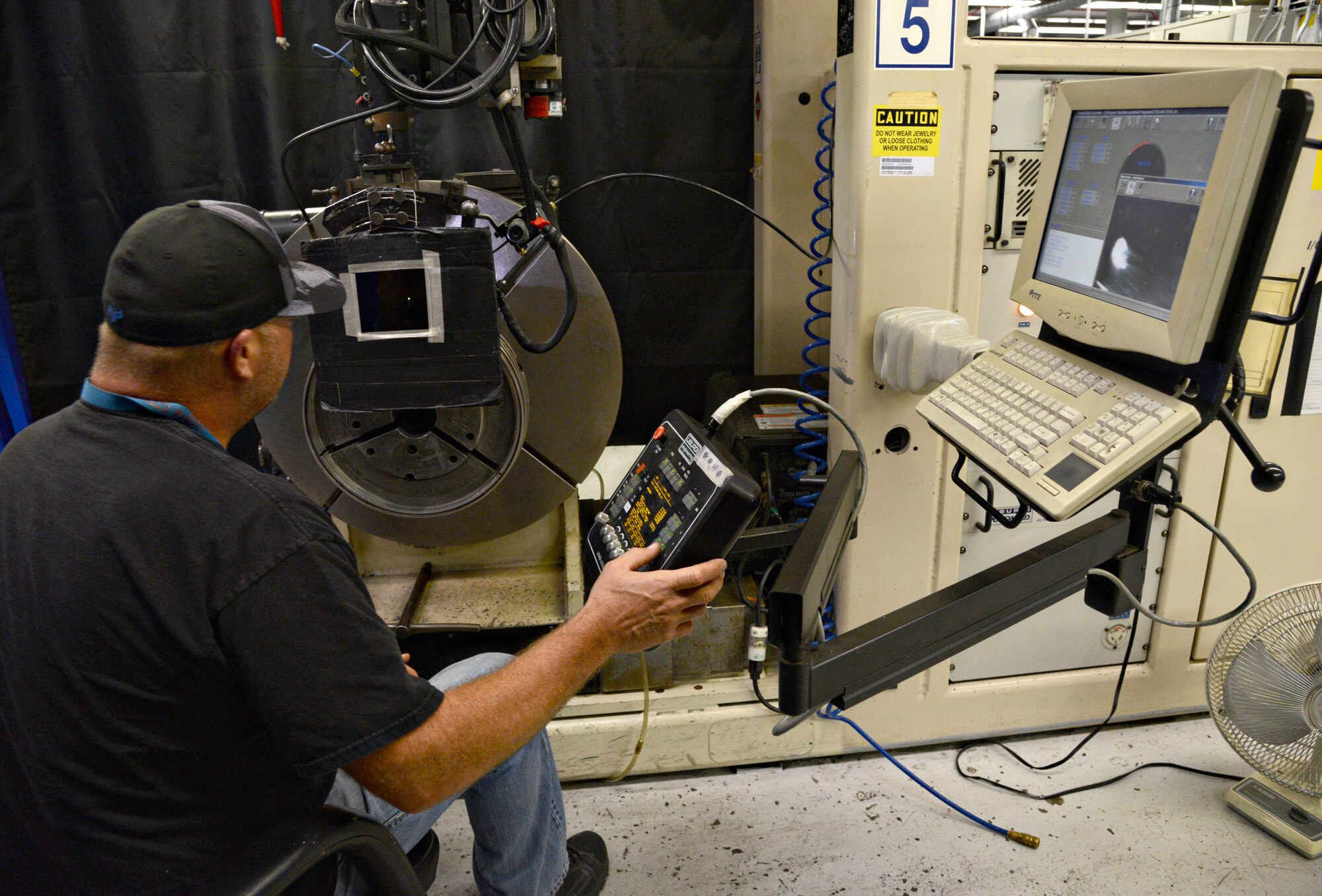 Deral Hunter monitors an automated machine that is welding a third stage turbine rotor air seal for a TF-33. The automated welding shop in Bldg. 3001 has eight out of the 10 Liburdi Automation machines on base. Tinker is the only Air Force base with an automated welding shop. The welders who work there have to go through a one-year formalized training program to be certified on the equipment. (Air Force photo by Kelly White/Released)