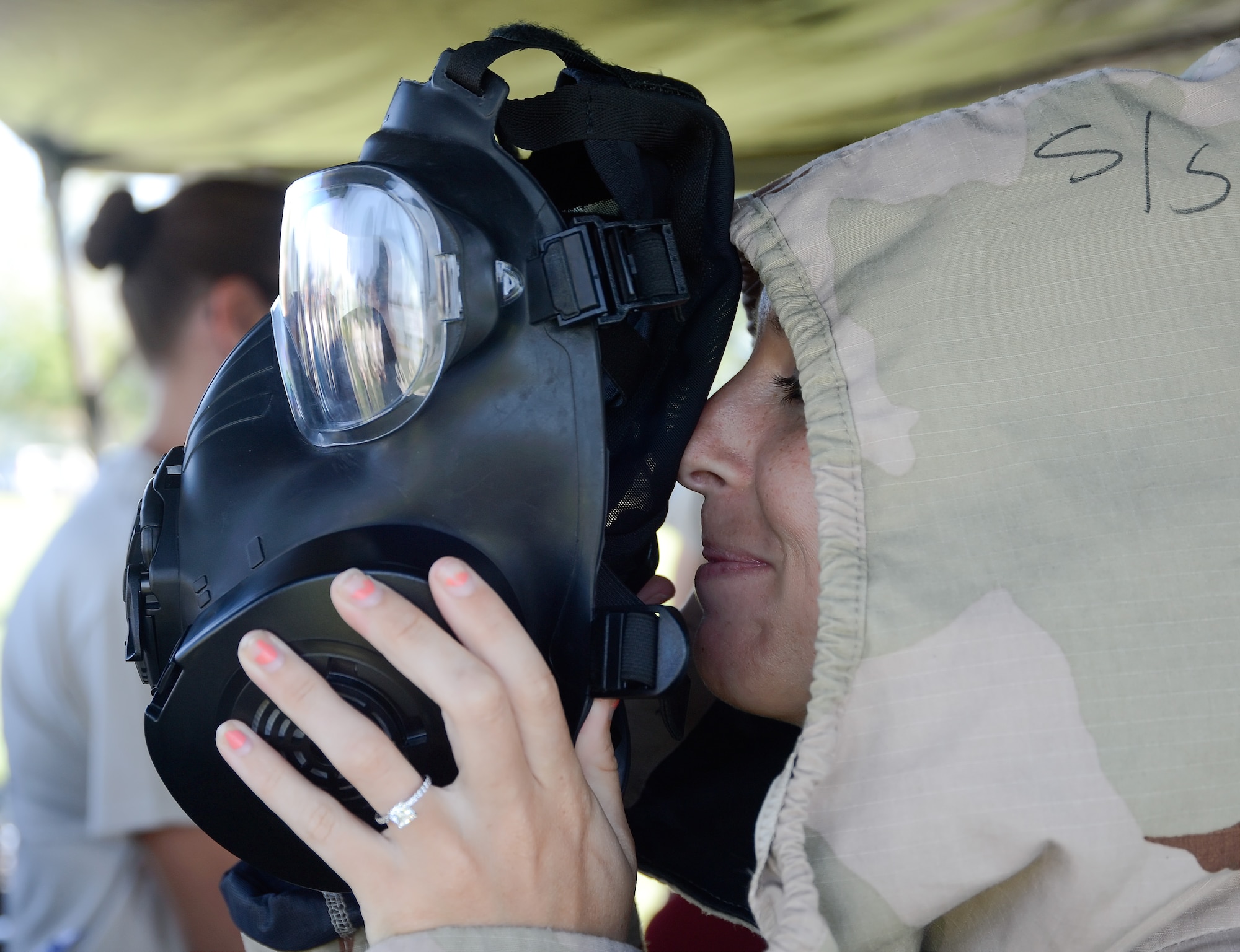 Kim Warriner, Welch Elementary School Kindergarten teacher, looks through a gas-mask while wearing full chemical protective gear during Operation Kids/Teachers Understanding Deployment Operations (KUDOS/TUDOS) Aug. 26, 2015, at the Youth Center on Dover Air Force Base, Del. Other teachers took pictures of Warriner as she demonstrated the size and bulk of the mask to them. (U.S. Air Force photo/Greg L. Davis)