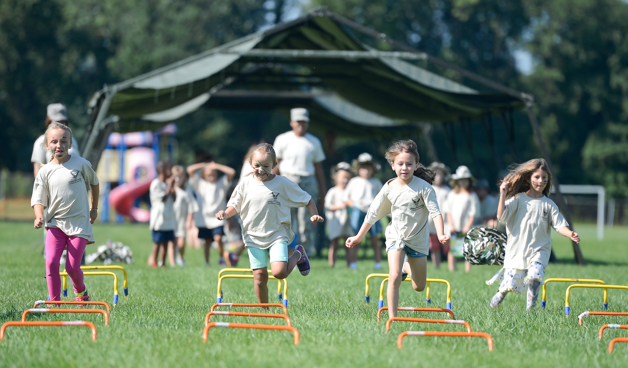 Four girls race through a short course of hurdles while participating in Dover Air Force Base???s Operation Kids/Teachers Understanding Deployment Operations (KUDOS/TUDOS) Aug. 26, 2015, at the Youth Center on Dover AFB, Del. The event sends kids and teachers through a simulated deployment processing line, obstacle course and other educational stations to give them a perspective on to how military members prepare and process to deploy. (U.S. Air Force photo/Greg L. Davis)