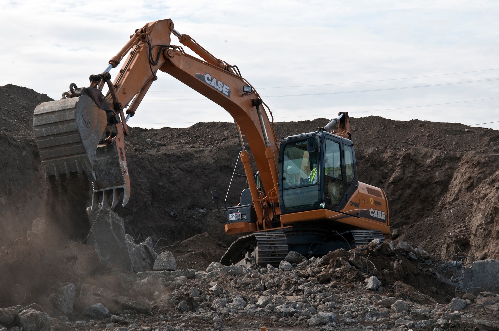 A member of the demolition team picks up the remaining concrete from a demolished munitions bunker Aug. 31, 2015, at Fairchild Air Force Base, Wash. The majority of the materials from the project are being recycled and reused including rebar found in the concrete structures. (U.S. Air Force photo/Airman 1st Class Mackenzie Richardson)