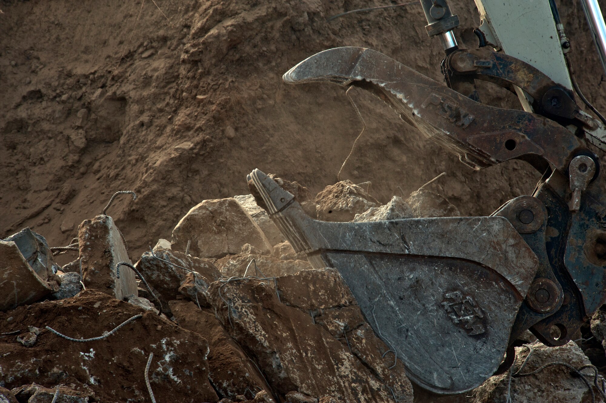 A member of the demolition team picks up the remaining concrete from a demolished munitions bunker Aug. 31, 2015, at Fairchild Air Force Base, Wash. The project is estimated to cost $3 million and to last until early next year. (U.S. Air Force photo/Airman 1st Class Mackenzie Richardson)