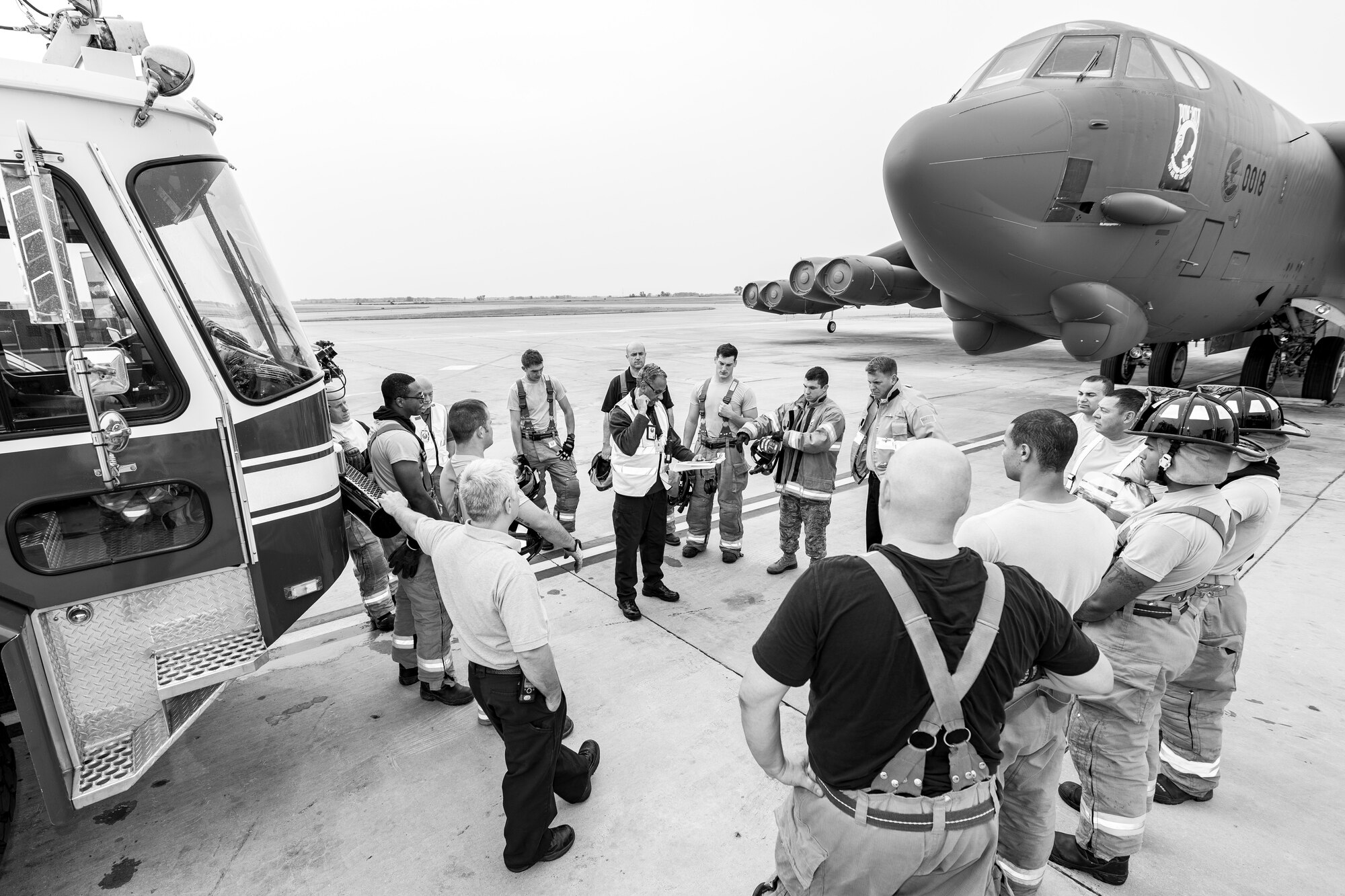 Charles Shipley, Inspector General inspector from Barksdale Air Force Base, gathers personnel from the 5th Civil Engineer Squadron on the flightline between a firetruck and a B-52H Stratofortress to discuss their training exercise at Minot Air Force Base, N.D., August 28, 2015. The exercise lasted about an hour and tested the ability of 15 members of the 5th CES fire department to work as a team. (U.S. Air Force photo/ Airman 1st Class Justin T. Armstrong)
