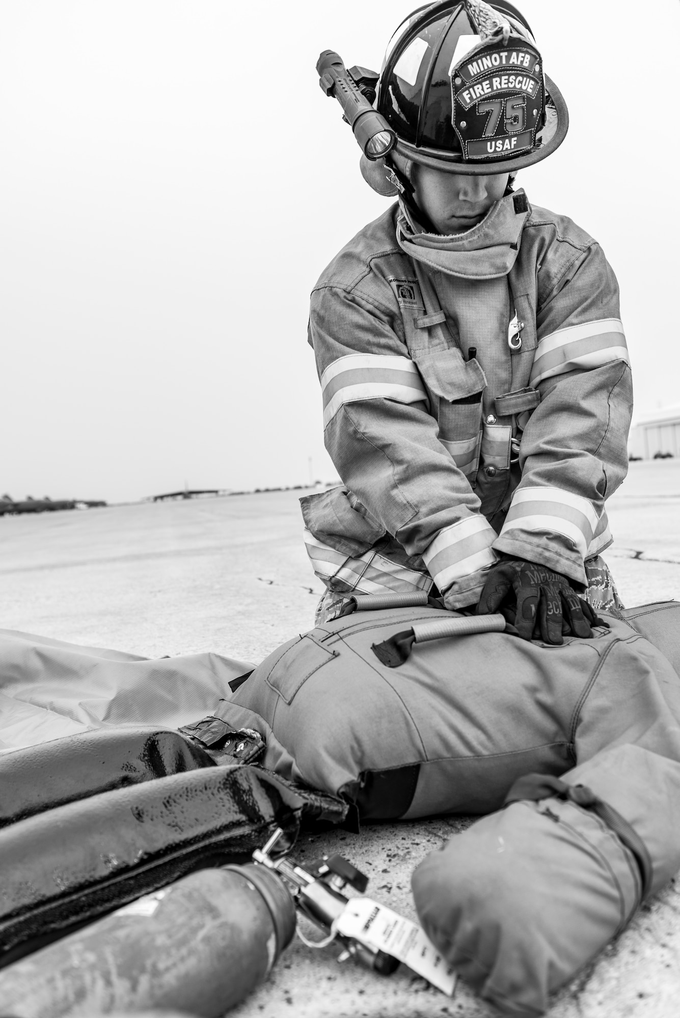 Senior Airman Nickolas Torrez, 5th Civil Engineer Squadron firefighter, performs CPR on a training dummy during an exercise at Minot Air Force Base, N.D., August 28, 2015. The two training dummies representing injured personnel, one in the cockpit and the other outside the aircraft, were used to test firefighters ability to evacuate victims from difficult locations. (U.S. Air Force photo/ Airman 1st Class Justin T. Armstrong)