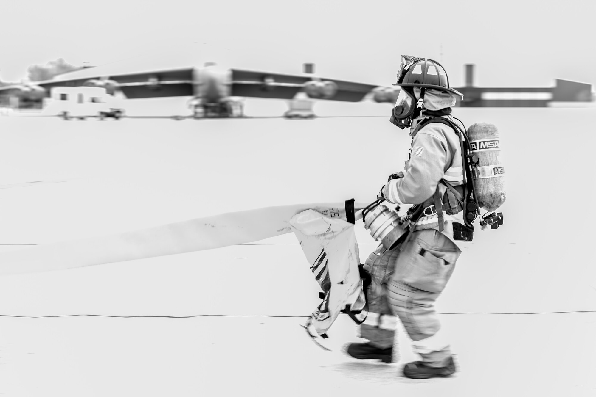 A firefighter from the 5th Civil Engineer Squadron pulls a hose across the flightline during a training exercise at Minot Air Force Base, N.D., August 28, 2015. The purpose of the exercise was to inspect and grade the department’s ability to accomplish the mission safely and work as a team.  (U.S. Air Force photo/ Airman 1st Class Justin T. Armstrong)