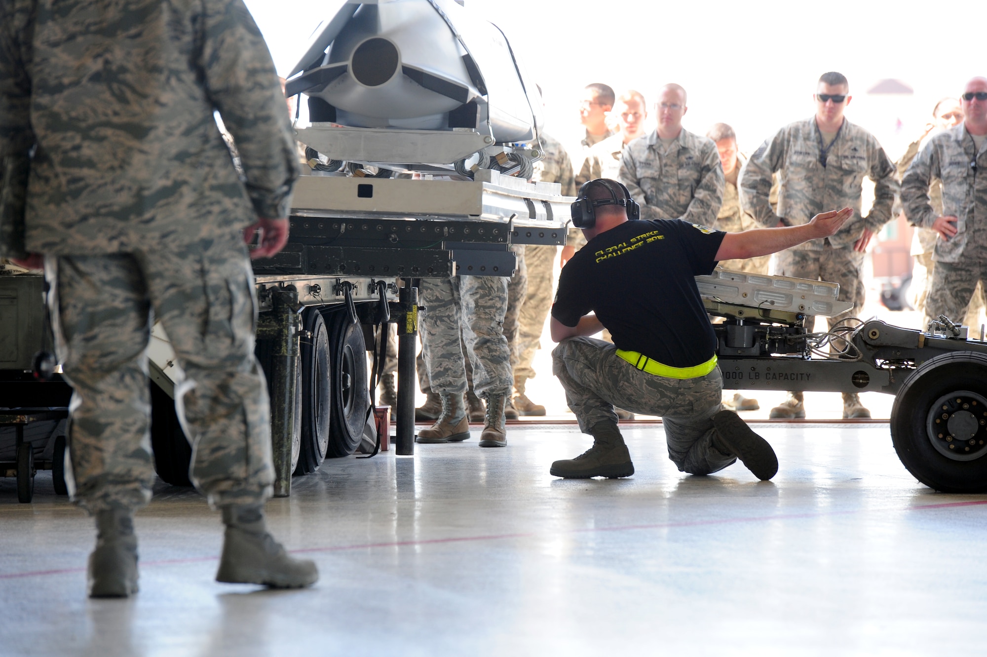Senior Airman Alexander Dickson, 509th Aircraft Maintenance Squadron aircraft armament system technician, guides the bomb lift operator towards a munition Aug. 11, 2015, at Whiteman Air Force Base, Mo. After the aircraft is prepared for the load, the munitions are removed from the trailer and secured to the suspension equipment of the aircraft. (U.S. Air Force photo by Airman 1st Class Jazmin Smith/Released)