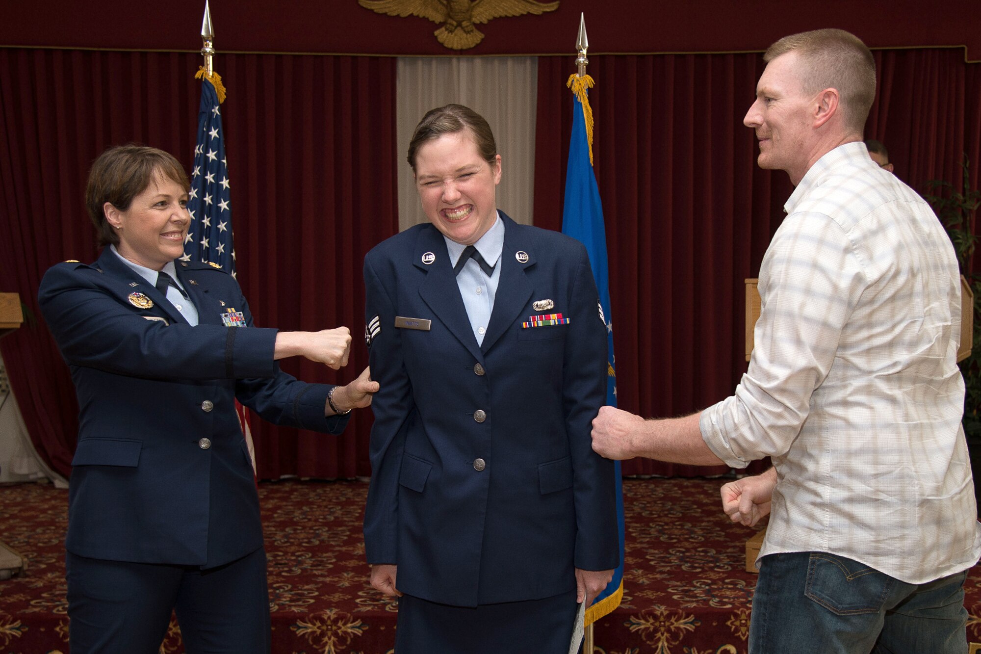 Senior Airman Kara Watts, 66th Comptroller Squadron administration specialist, has her new stripes tacked on by her parents, Maj. Tobie Wethington, and her dad, Brian, during the June enlisted promotion ceremony at the Minuteman Commons June 30. Both Watts and her mother are serving on active duty at the same time. (U.S. Air Force photo by Mark Herlihy)
