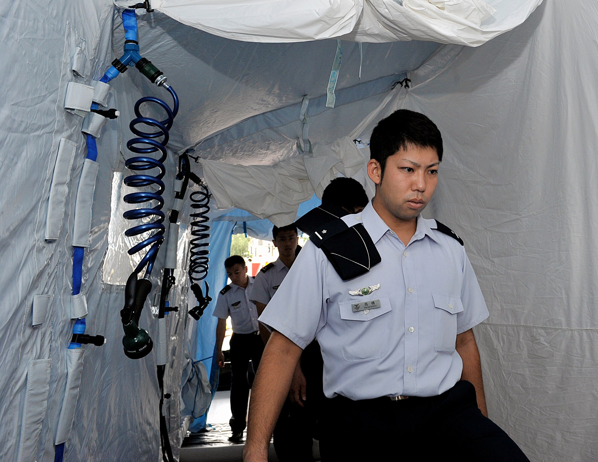 Japan Air Self-Defense Force students from the 3rd Technical School, walk through the inside of a decontamination tent during their tour on Kadena Air Base, Japan, Sept. 2, 2015. Nine JASDF students had an opportunity to interact with Airmen and learn about Kadena's explosive ordnance disposal systems, mission and capabilities during the tour. (U.S. Air Force photo by Naoto Anazawa)