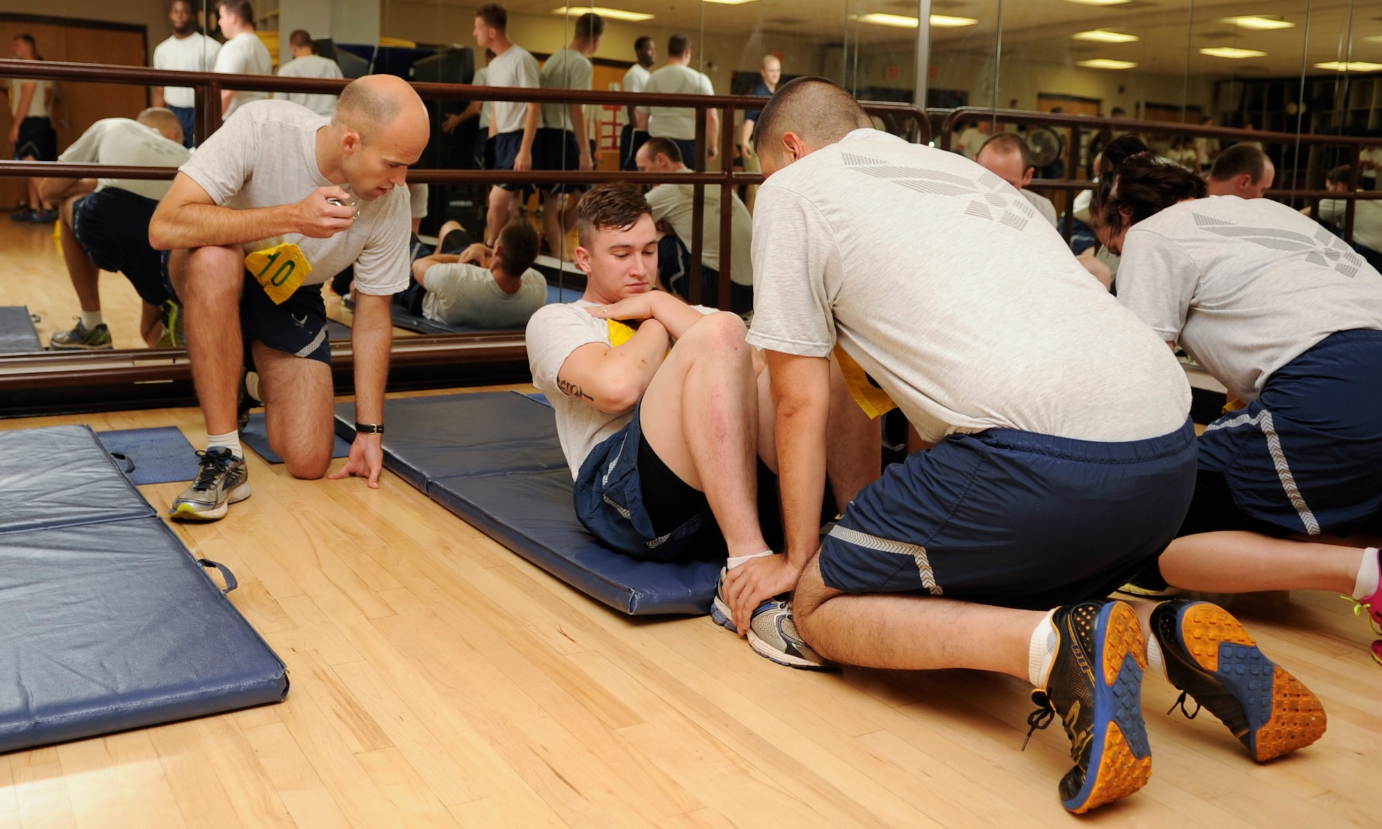 U.S. Air Force Airmen execute the timed sit up portion of the Air Force fitness assessment at Davis-Monthan Air Force Base, Ariz., July 27, 2015. The FA consists of a body composition assessment, to include height and weight measurements and waist circumference measurements, timed pushups and sit ups and a 1.5 mile run. (U.S. Air Force photo by Airman 1st Class Mya M. Crosby/Released)
