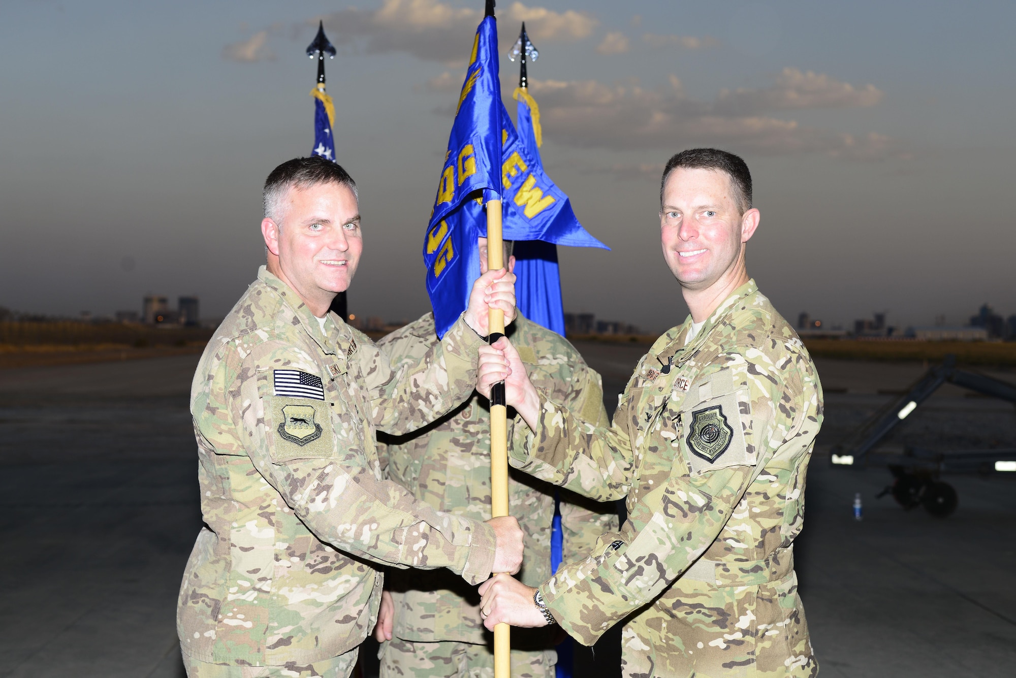 U.S. Air Force Col. Michael Koscheski, 332nd Air Expeditionary Wing commander, passes the guidon to Col. Gregory Roberts, 1st Expeditionary Rescue Group commander, during the 1st Expeditionary Rescue Group activation and assumption of command ceremony at an undisclosed location in Southwest Asia, Sept. 1, 2015. Roberts assumed command after serving as the Strategic Planning Process Branch, J-5 Directorate chief at headquarters U.S. Special Operations Command at MacDill Air Force Base, Fla. U.S. (Air Force photo by Senior Airman Racheal E. Watson/Released)