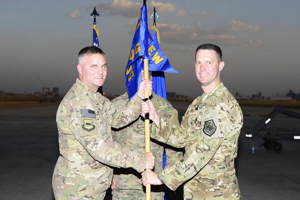 U.S. Air Force Col. Michael Koscheski, 332nd Air Expeditionary Wing commander, passes the guidon to Col. Gregory Roberts, 1st Expeditionary Rescue Group commander, during the 1st Expeditionary Rescue Group activation and assumption of command ceremony at an undisclosed location in Southwest Asia, Sept. 1, 2015. Roberts assumed command after serving as the Strategic Planning Process Branch, J-5 Directorate chief at headquarters U.S. Special Operations Command at MacDill Air Force Base, Fla. U.S. (Air Force photo by Senior Airman Racheal E. Watson/Released)