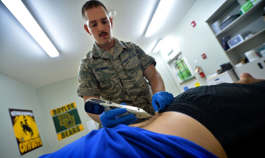 Capt. Joshua, 380th Expeditionary Medical Squadron physical therapist, applies heat to needles to help relieve a patient’s back injury at an undisclosed location in Southwest Asia Sept. 1, 2015. The physical therapy team is responsible for evaluating patients and utilizing different therapeutic procedures to help restore patient functions. (U.S. Air Force photo/Tech. Sgt. Jeff Andrejcik)  