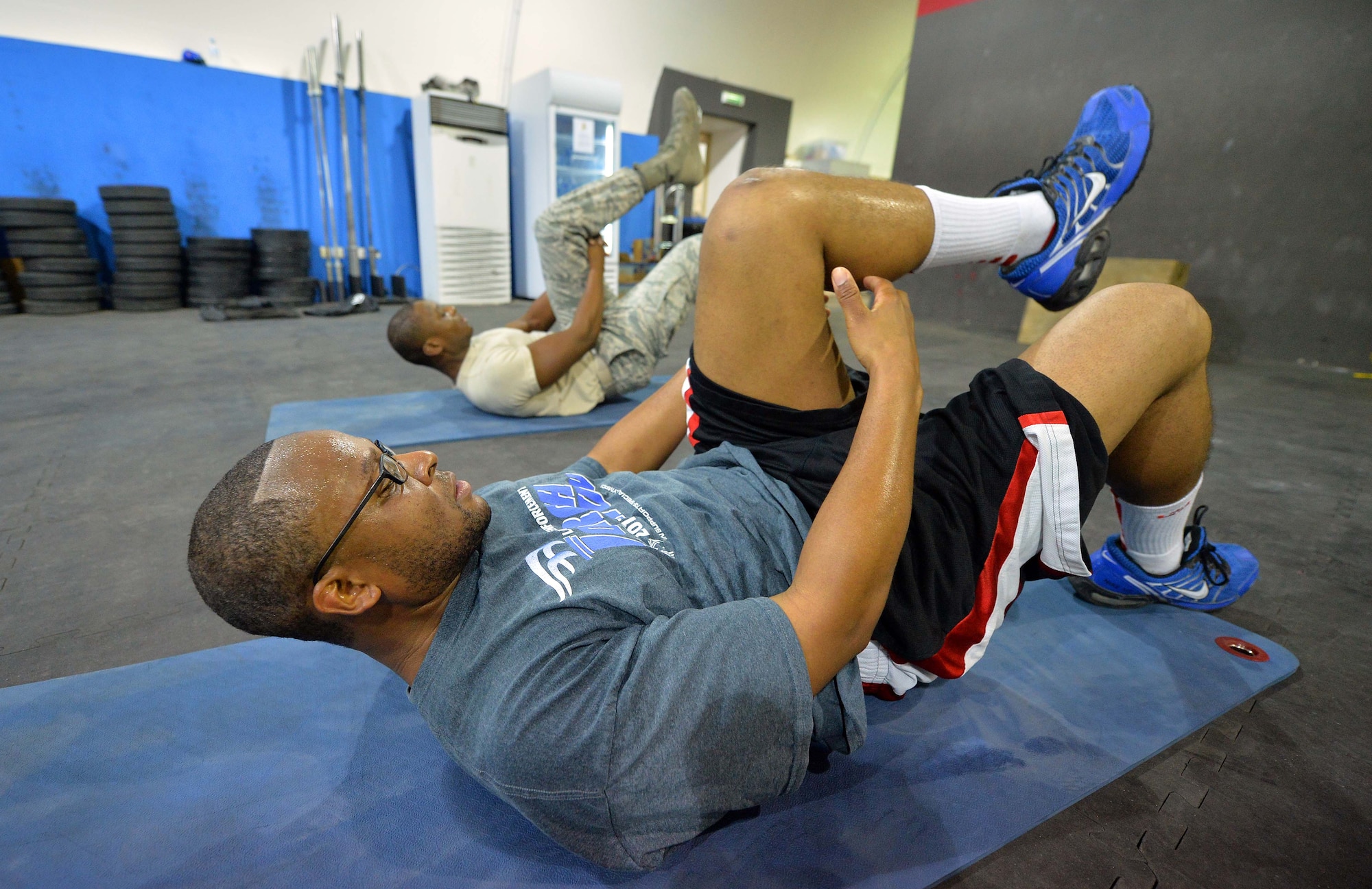 Staff Sgt. Jamey, 380th Expeditionary Security Forces Squadron member, and Senior Airman Akil, 380th Expeditionary Medical Group noncommissioned officer in charge physical therapy clinic, stretch after completing strength and agility training at undisclosed location in Southwest Asia Sept. 3, 2015. The physical therapy team uses the strength and agility program as a method to help restore physical abilities. (U.S. Air Force photo/Tech. Sgt. Jeff Andrejcik)  