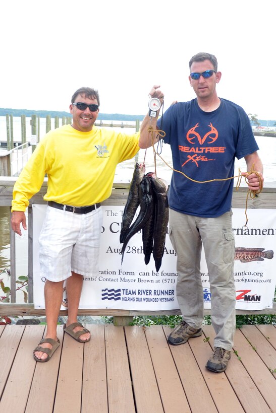 Kirk Lowe winner of the snakehead division in the Town of Quantico Fishing Tournament and the Town of Quantico mayor Kevin P. Brown, right, weighs in Northern snakeheads caught in the Potomac River during the Quantico Classic Fishing Tournament from Aug. 28-29.  Since 2004, the snakehead has been detected as part of the Potomac River aquatic population. This invasive species of fish has been known to feed on naturalized fish in the Potomac.