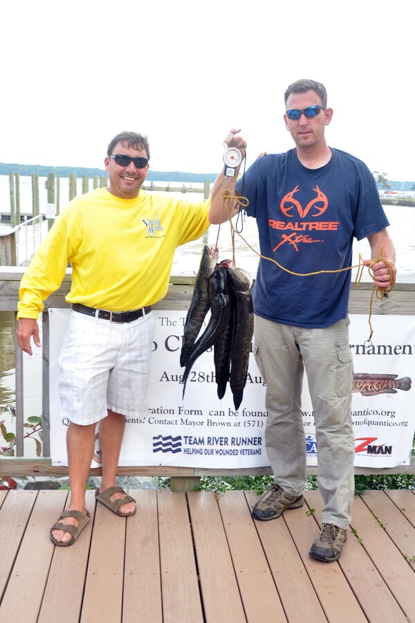 Kirk Lowe winner of the snakehead division in the Town of Quantico Fishing Tournament and the Town of Quantico mayor Kevin P. Brown, right, weighs in Northern snakeheads caught in the Potomac River during the Quantico Classic Fishing Tournament from Aug. 28-29.  Since 2004, the snakehead has been detected as part of the Potomac River aquatic population. This invasive species of fish has been known to feed on naturalized fish in the Potomac.