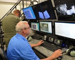 Gene Ernst, a civilian flight refueling instructor, helps Nebraska Air National Guard boom operators hone their skills refueling aircraft in the newly acquired boom operator simulator located at the 155th Air Refueling Wing, Lincoln, Nebraska, Aug. 25, 2015. The Nebraska Air Guard is the first Guard unit to receive the BOSS 59-1495.