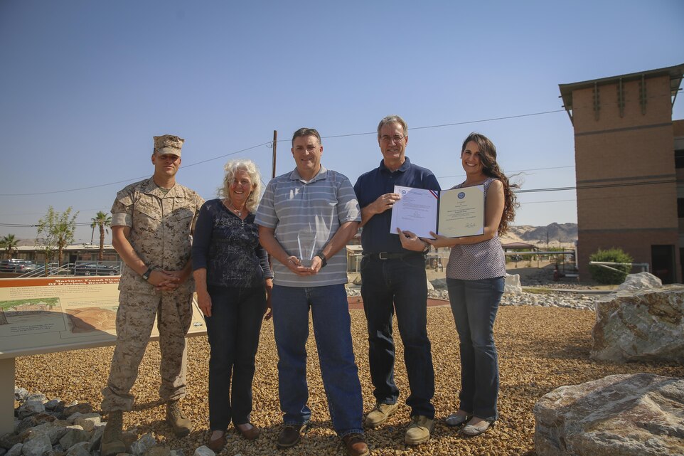Members of Natural Resources and Environmental Affairs, proudly display their 2015 Sustainability, Non-Industrial Installation Awards from the Secretary of the Navy and Secretary of Defense, outside of the NREA building, Aug. 18, 2015. NREA was recognized for their achievements in May. (Official Marine Corps photo by Lance Cpl. Medina Ayala-Lo/Released)