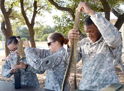 (From left) Specialists Christina Laufer, Emily Maloney and Brian Hendry, with U.S. Army South's Operations Company, prepare drums of ammunition for the M249 range at Camp Bullis Aug. 25.