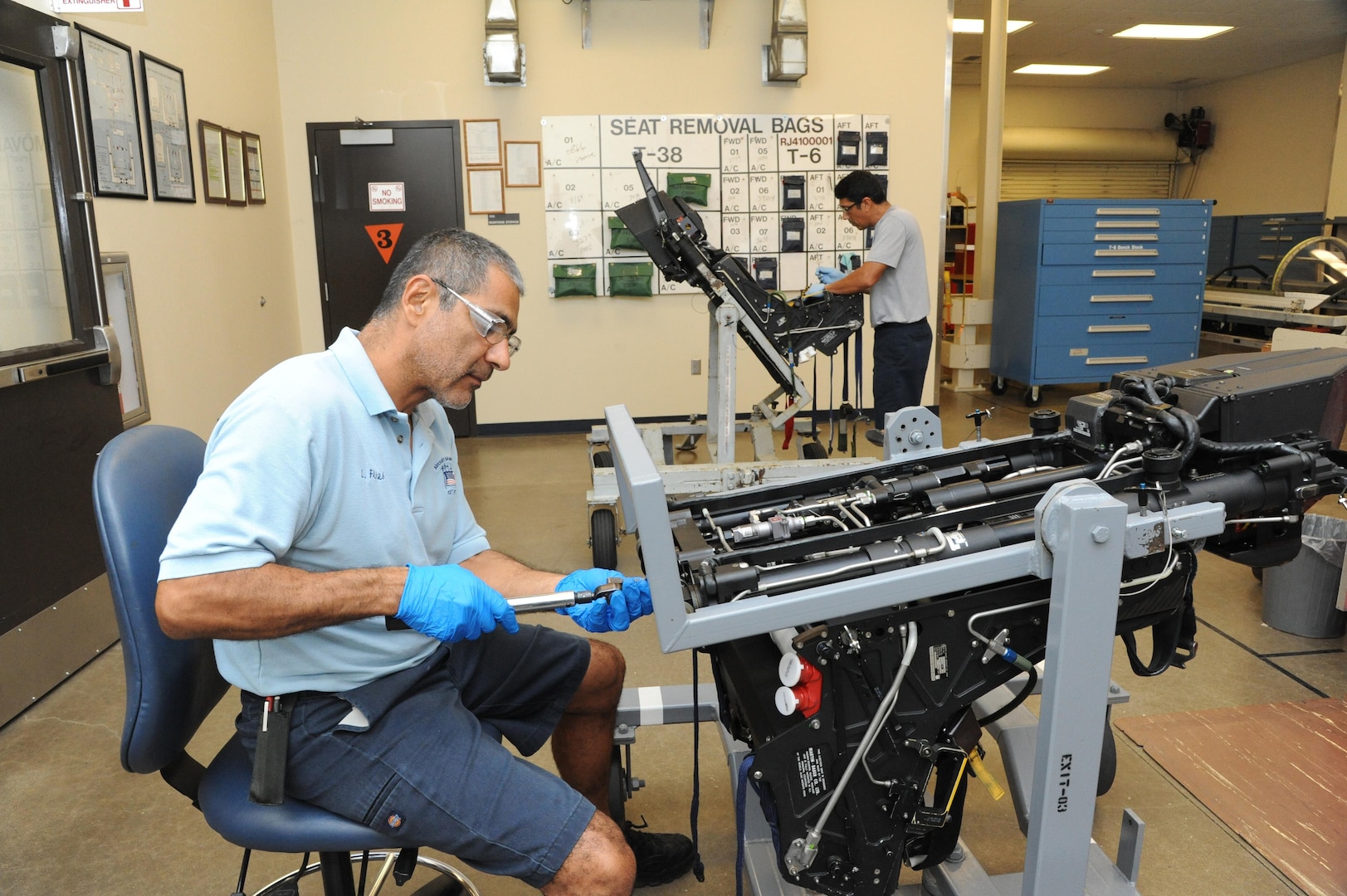 Leroy Flores (left), and Romero Bazan, 12th Flying Training Wing Maintenance, egress technicians, works on the primary catapult of the T-6 Texan during the aircraft's phase maintenance inspection seat Aug. 17, 2015, at Joint Base San Antonio-Randolph.   To ensure aircraft remain operational 12 FTW maintenance personnel conducting phase maintenance is essential to make sure every part of the aircraft is in working order.  